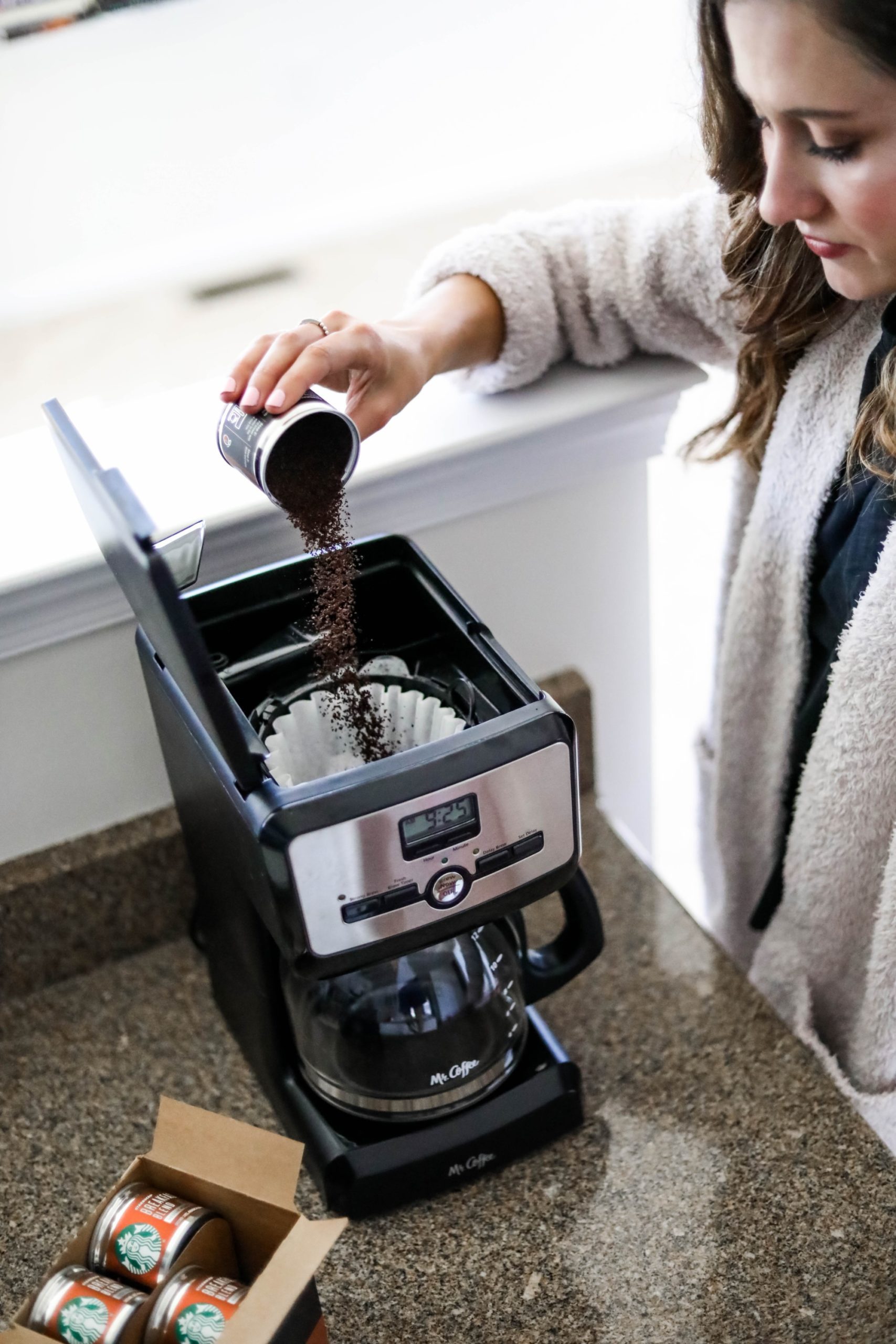 woman pouring starbucks breakfast blend cans into coffee maker 